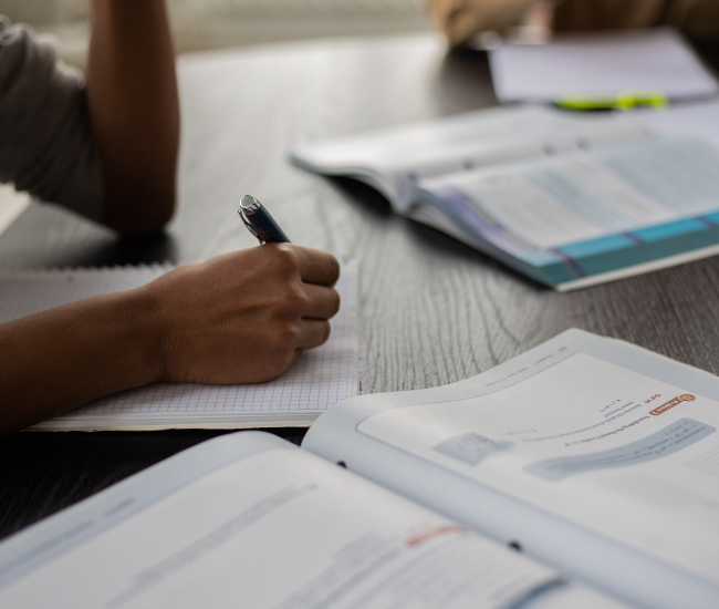 Person studying in front of sprawled out textbooks and notepad